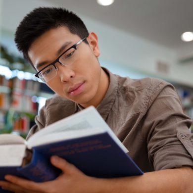 Asian male student reading book in university